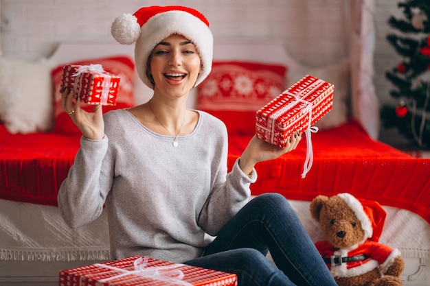 Mujer con regalos de navidad por arbol de navidad