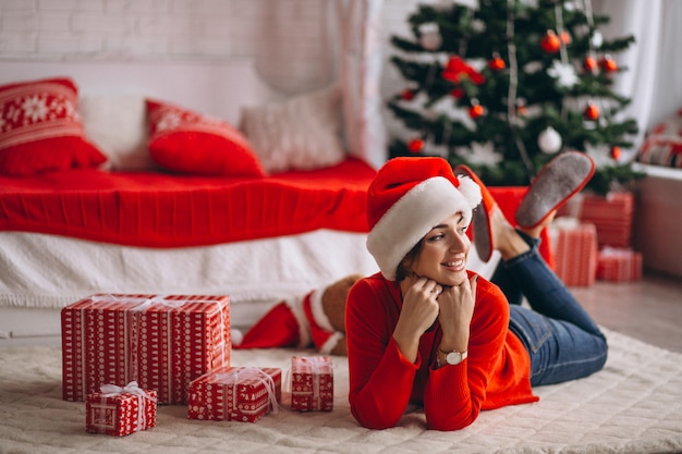 Mujer con regalos de navidad por arbol de navidad