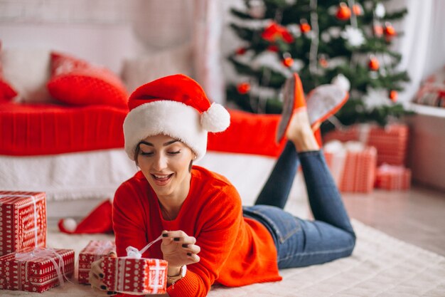 Mujer con regalos de navidad por arbol de navidad