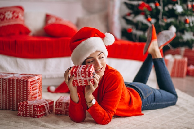 Mujer con regalos de navidad por arbol de navidad