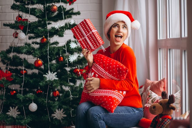 Mujer con regalos de navidad por arbol de navidad