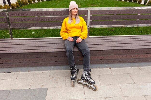 Foto gratuita mujer relajada con patines sentado en un banco