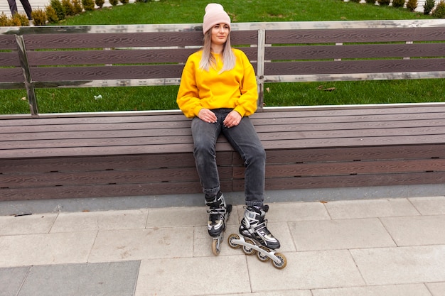 Mujer relajada con patines sentado en un banco