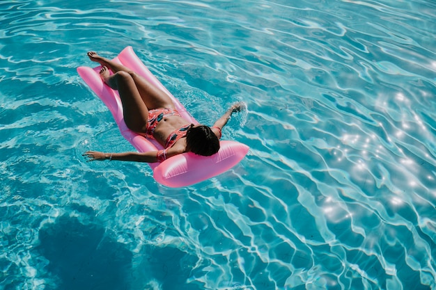 Mujer relajando en flotador en la piscina