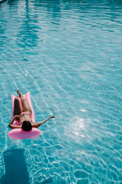 Mujer relajando en flotador en la piscina