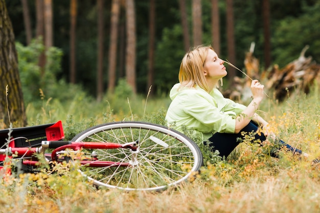 Foto gratuita mujer relajante al lado de la bicicleta y mirando a otro lado