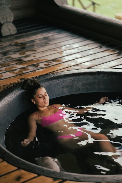 Mujer relajante en el cuidado de la piel orgánico redondo baño al aire libre en baño caliente