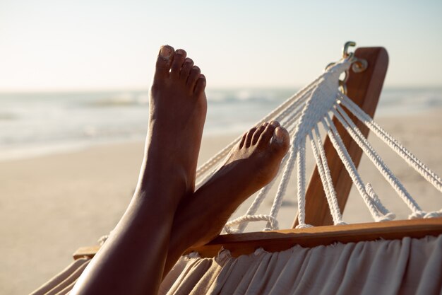 Mujer relajante con los pies en una hamaca en la playa