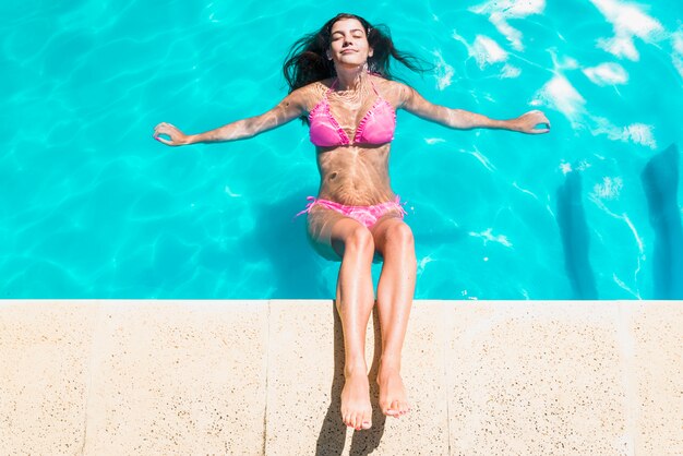 Mujer relajante en piscina con los ojos cerrados