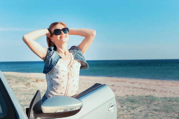 Mujer relajante en la playa en el coche