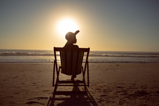 Mujer relajante en una silla de playa en la playa