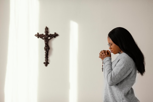 Foto gratuita mujer religiosa rezando con rosario en casa