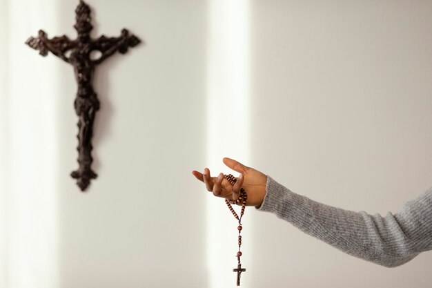 Mujer religiosa rezando con rosario en casa