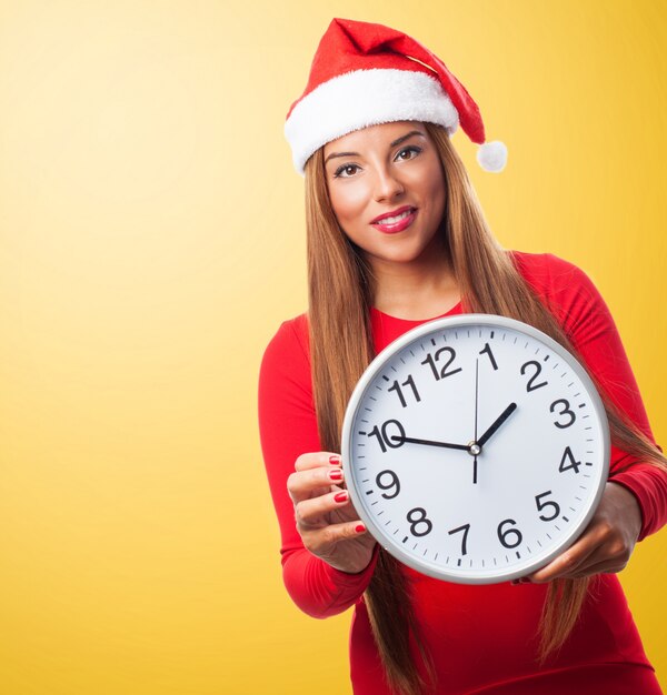 Mujer con un reloj grande y el sombrero de papa noel