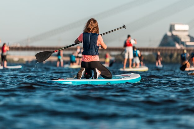 Mujer remando con tablas de paddle surf a lo largo del río