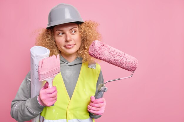 mujer reparadora piensa en el diseño de la casa lleva plano rodillo y cepillo vestido con ropa de trabajo