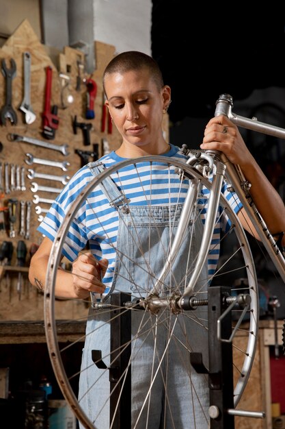 Mujer reparando bicicleta tiro medio