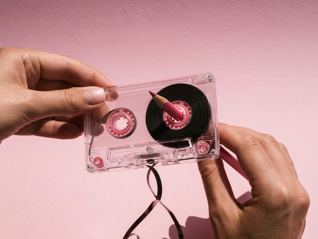 Mujer reparando cinta de cassette rota con lápiz rosa
