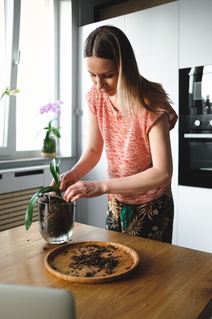 Mujer replantando flores usando instrucciones en línea en la computadora portátil