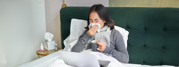 Foto gratuita mujer con resfriado que tiene gripe y se queda en la cama estornudando en una servilleta, secreción nasal y síntomas de influenza