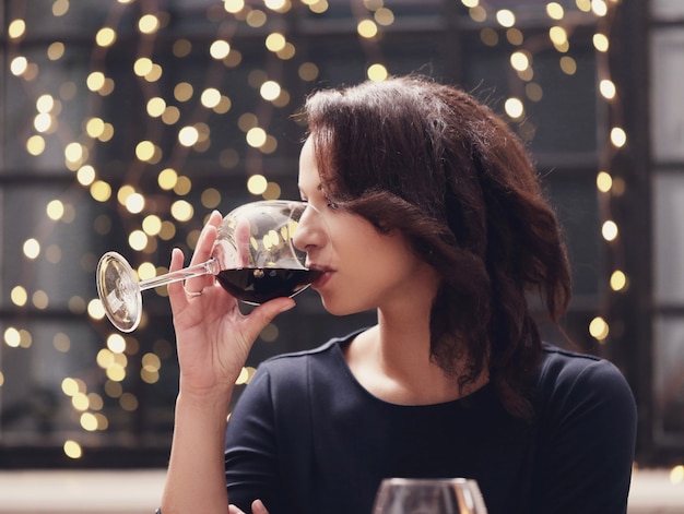 Mujer en restaurante bebiendo una copa de vino