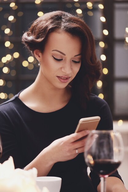 Mujer en restaurante usando el teléfono inteligente