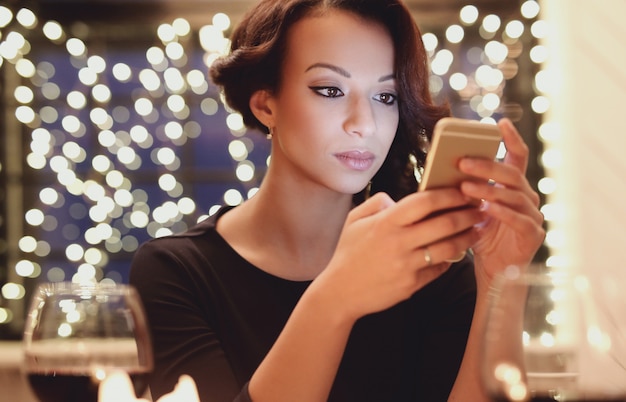 Mujer en restaurante usando el teléfono inteligente