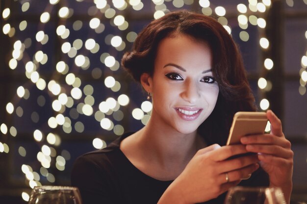 Mujer en restaurante usando el teléfono inteligente