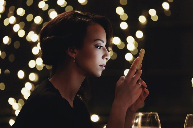 Mujer en restaurante usando el teléfono inteligente