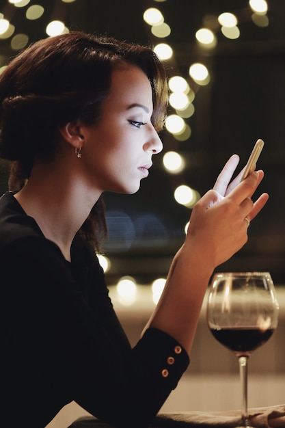 Mujer en restaurante usando el teléfono inteligente