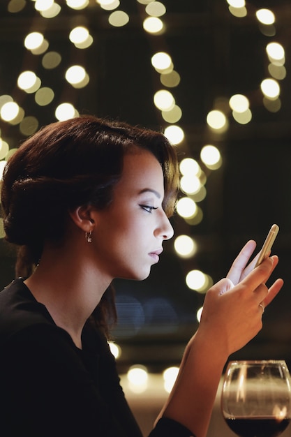 Mujer en restaurante usando el teléfono inteligente