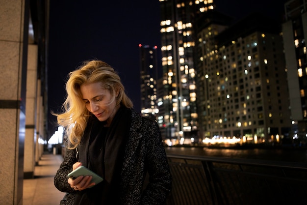 Mujer revisando su teléfono inteligente al aire libre en la ciudad