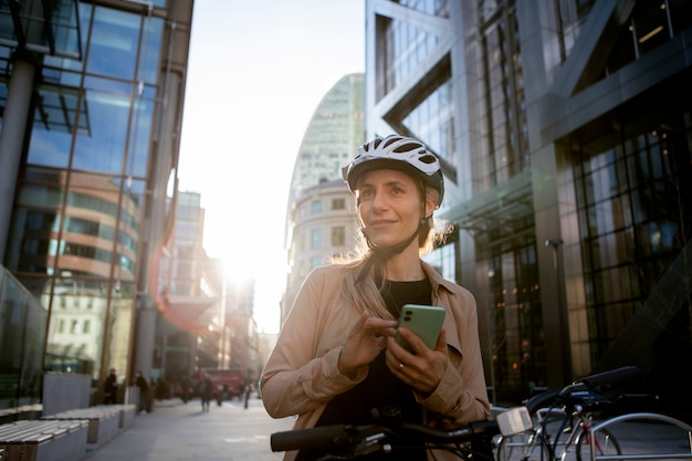 Mujer revisando su teléfono inteligente mientras está sentada en una bicicleta