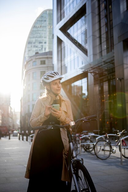 Mujer revisando su teléfono inteligente mientras está sentada en una bicicleta