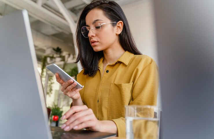 Foto gratuito mujer revisando su teléfono mientras trabaja