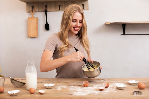 Foto gratuita mujer revuelva los huevos y la leche en el recipiente metálico