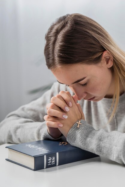 Mujer rezando con biblia y collar cruzado