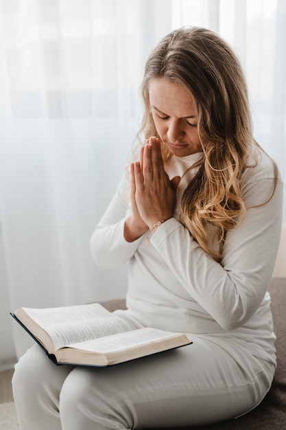 Mujer rezando mientras lee la Biblia