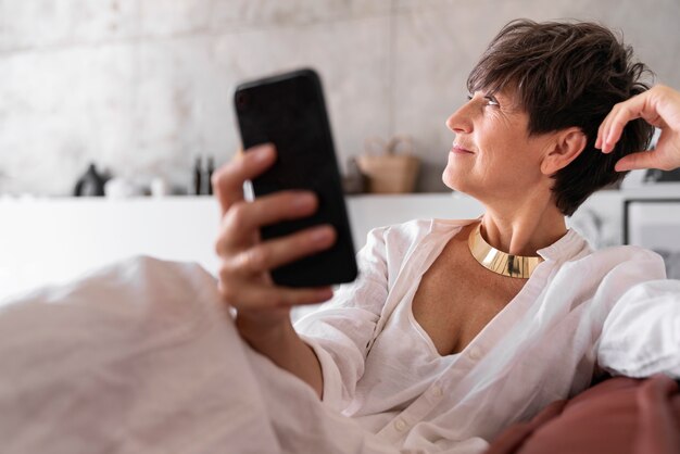 Mujer rica de tiro medio con teléfono inteligente