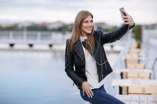 Mujer riendo apoyada en una barandilla haciéndose una autofoto