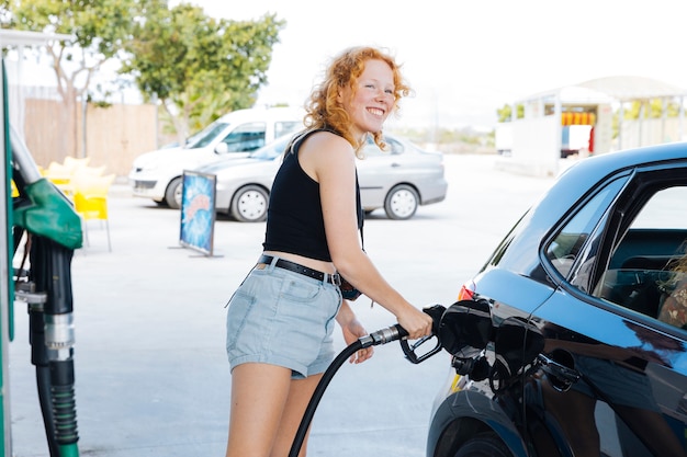 Foto gratuita mujer riendo llenando el coche en la estación de servicio