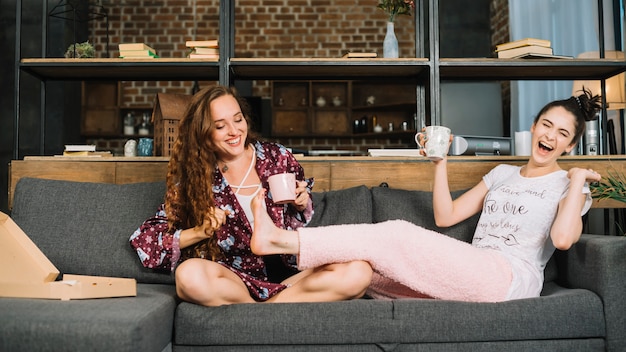 Mujer riendo mientras su amiga haciendo cosquillas en los pies