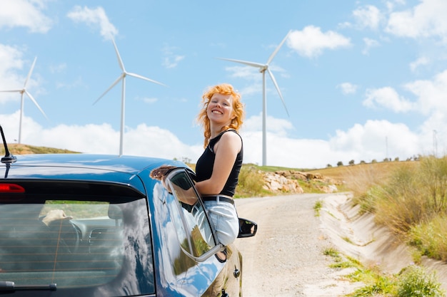 Mujer riendo y mirando a cámara fuera de la ventana del coche