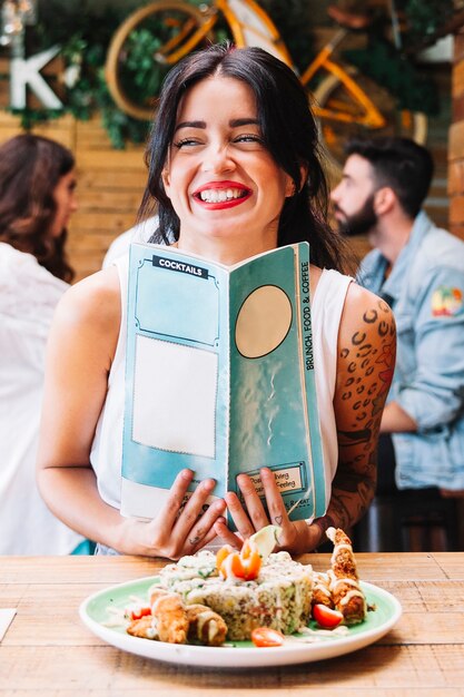 Mujer riendo con plato y menú