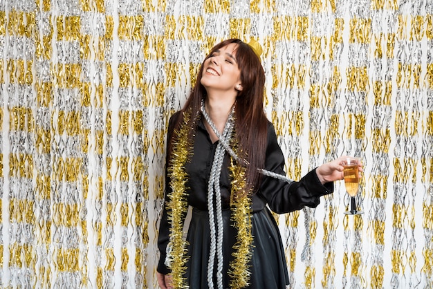 Mujer riendo en ropa de noche con vaso de bebida