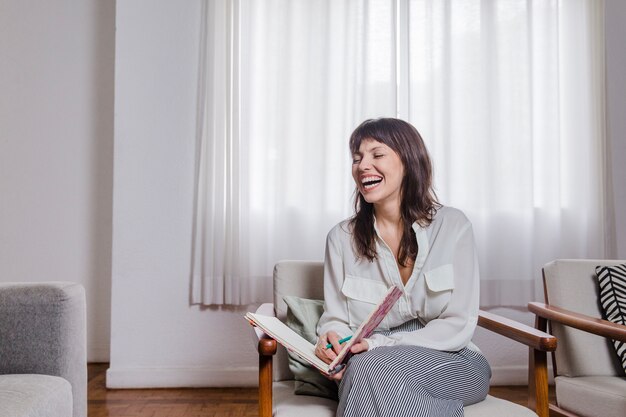 Mujer riendo en silla con libro