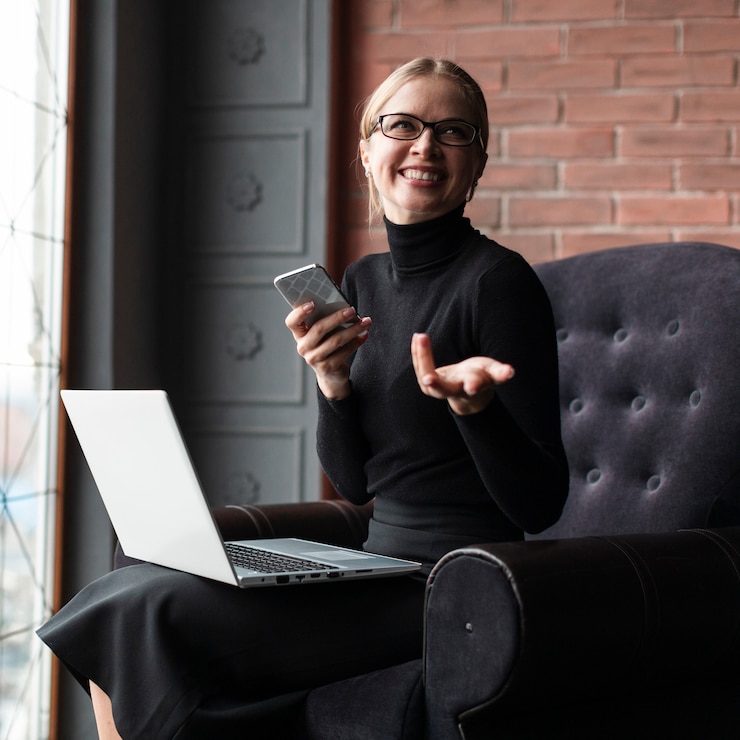 Foto gratuito mujer riendo con teléfono y computadora portátil