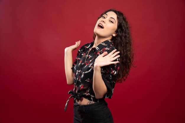 Mujer rizada con blusa negra de pie.