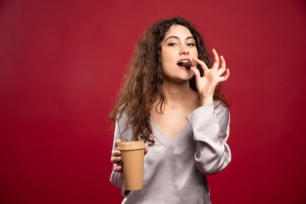 Mujer rizada comiendo chocolate.