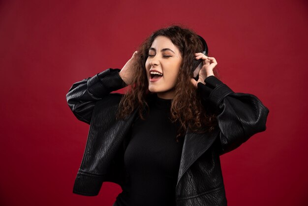 Mujer rizada escuchando música y cantando.